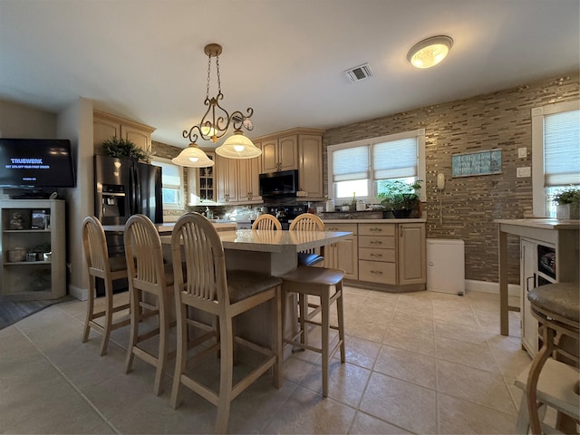 kitchen with range, light brown cabinets, light tile patterned floors, stainless steel fridge, and a kitchen island