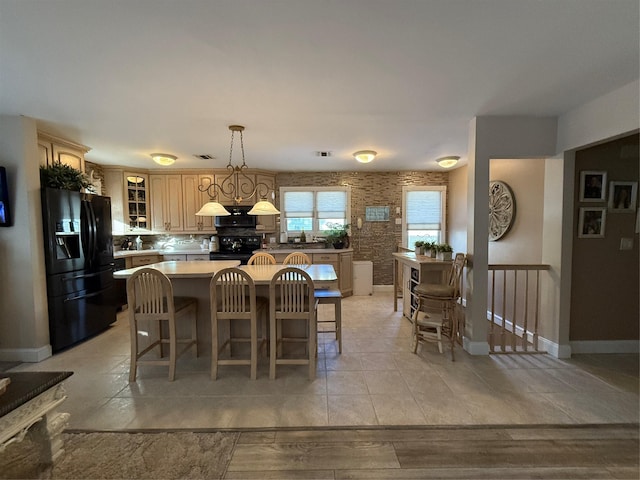 kitchen featuring a breakfast bar, light wood-type flooring, a kitchen island, pendant lighting, and black appliances