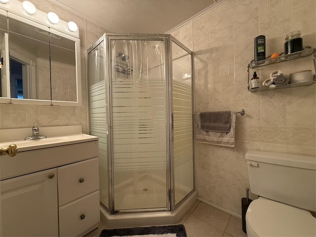 bathroom with toilet, a shower with shower door, tile walls, vanity, and tile patterned flooring