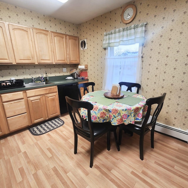 dining room featuring a baseboard radiator, sink, and light wood-type flooring