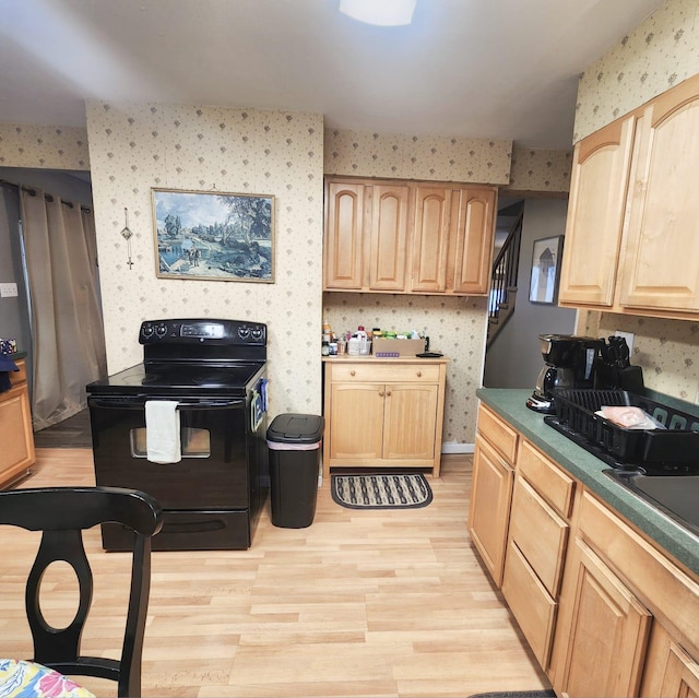 kitchen with black electric range oven, light brown cabinets, and light hardwood / wood-style floors