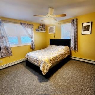 bedroom featuring ceiling fan, multiple windows, and a baseboard heating unit