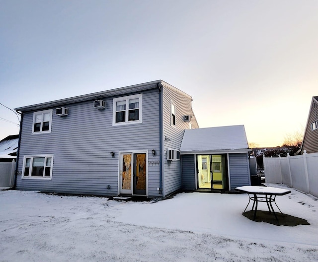 snow covered house featuring a wall unit AC