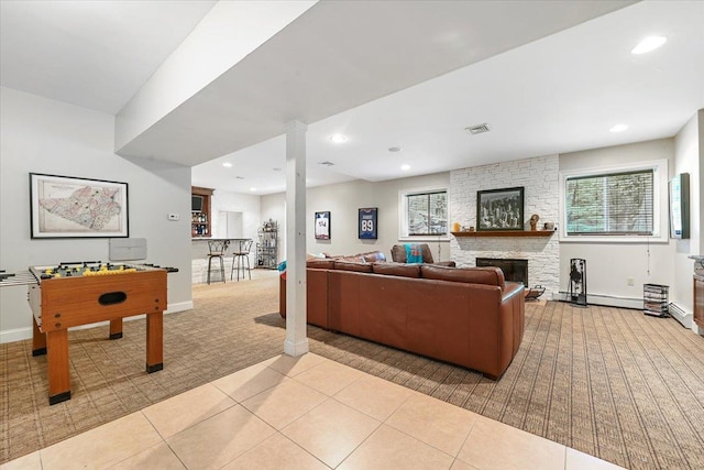 tiled living room with a stone fireplace