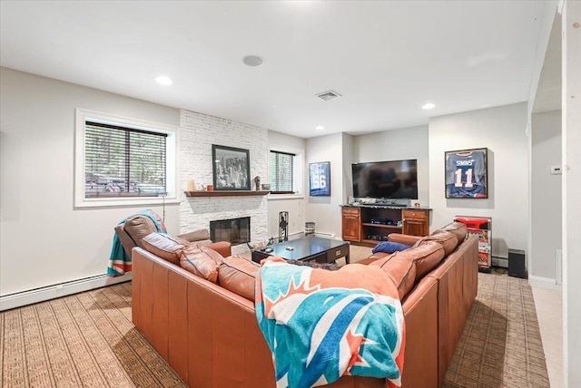 living room featuring baseboard heating, plenty of natural light, and a fireplace