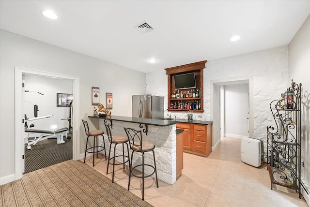 bar with stainless steel fridge, sink, and light tile patterned floors