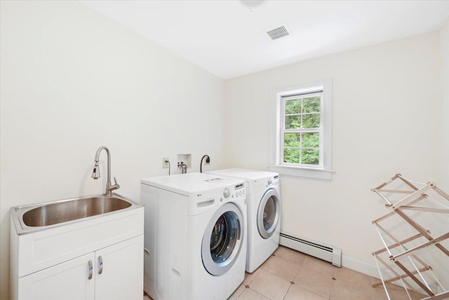 washroom with light tile patterned floors, sink, a baseboard heating unit, washing machine and dryer, and cabinets