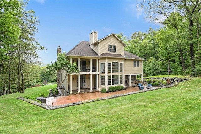 back of house with a balcony, a patio, and a lawn