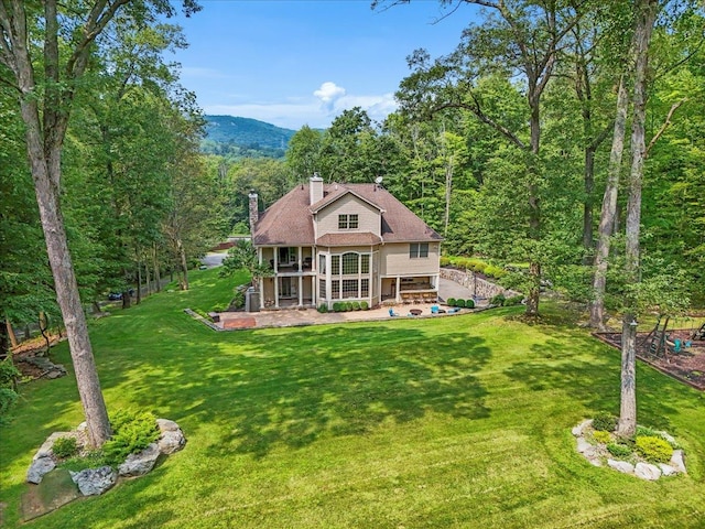 rear view of property with a mountain view, a patio area, and a lawn