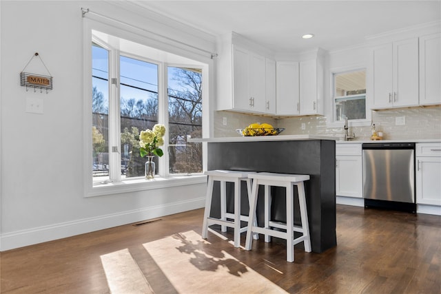 kitchen featuring sink, white cabinetry, stainless steel dishwasher, dark hardwood / wood-style floors, and decorative backsplash