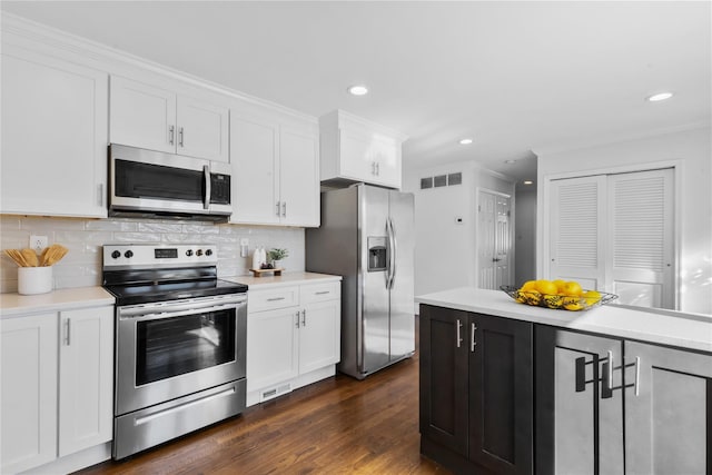 kitchen with dark hardwood / wood-style floors, white cabinets, backsplash, stainless steel appliances, and crown molding