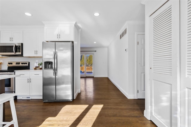 kitchen featuring dark wood-type flooring, crown molding, stainless steel appliances, decorative backsplash, and white cabinets