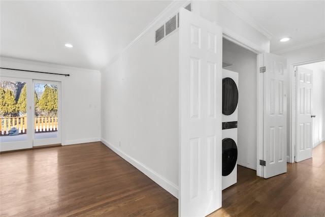 washroom with ornamental molding, stacked washer / dryer, and dark hardwood / wood-style flooring