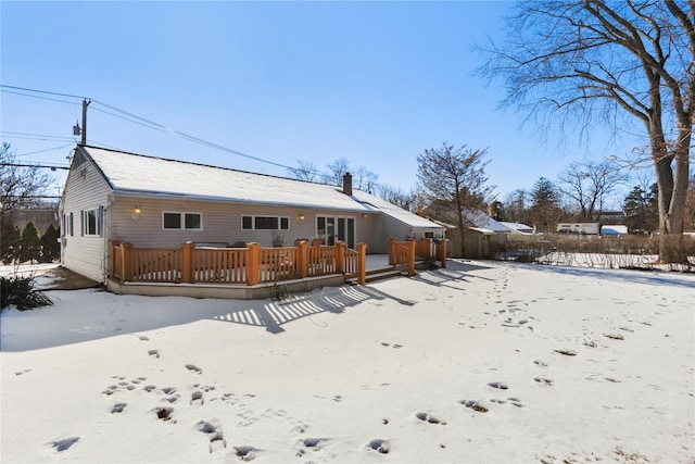 snow covered back of property with a wooden deck