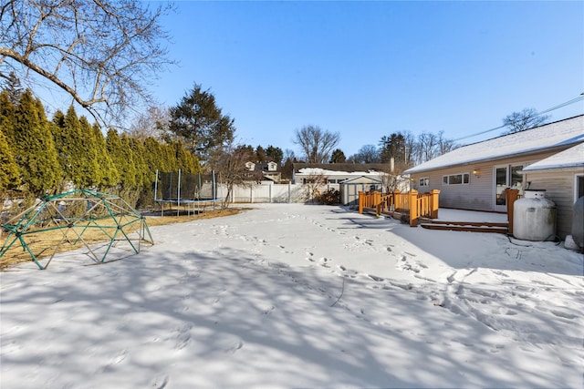 yard covered in snow featuring a deck and a trampoline