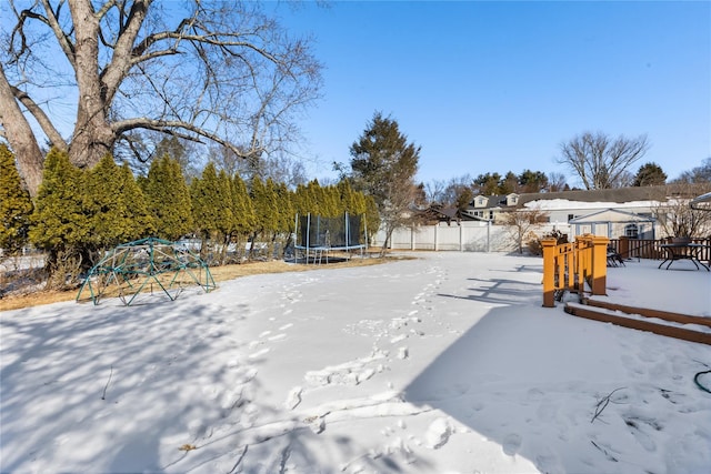 yard layered in snow with a trampoline