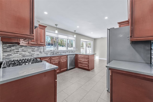 kitchen featuring appliances with stainless steel finishes, decorative light fixtures, tasteful backsplash, light stone counters, and kitchen peninsula