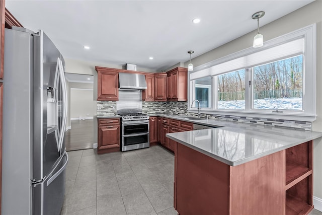 kitchen with decorative light fixtures, sink, kitchen peninsula, stainless steel appliances, and wall chimney exhaust hood