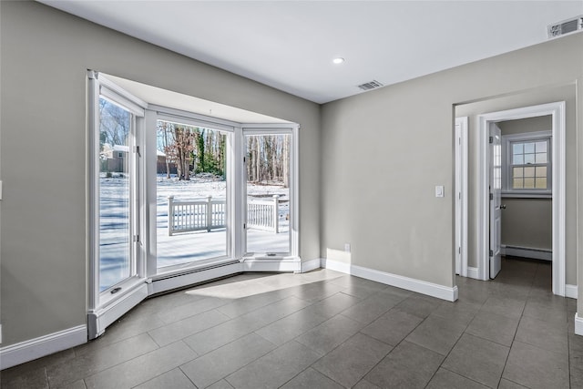 unfurnished room featuring a baseboard heating unit and dark tile patterned flooring