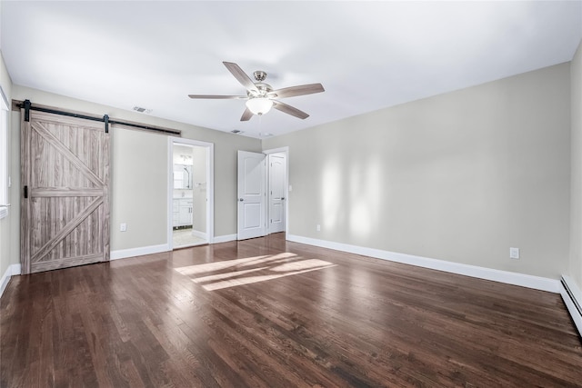 spare room featuring baseboard heating, ceiling fan, wood-type flooring, and a barn door