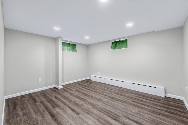 spare room featuring baseboard heating and hardwood / wood-style flooring