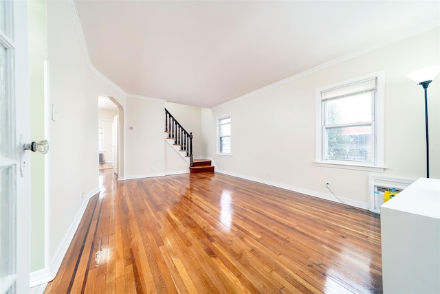 unfurnished living room featuring hardwood / wood-style floors, crown molding, and a wall mounted air conditioner