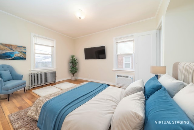 bedroom featuring hardwood / wood-style floors, radiator heating unit, ornamental molding, and a wall mounted AC