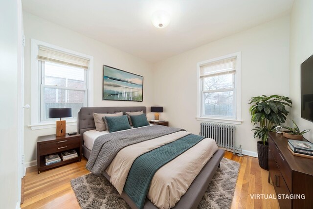 bedroom with multiple windows, radiator, and light hardwood / wood-style flooring