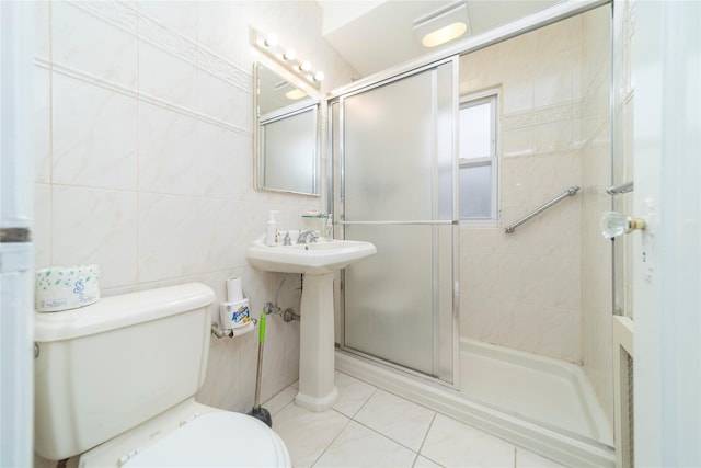 bathroom featuring tile patterned flooring, a shower with door, tile walls, and toilet