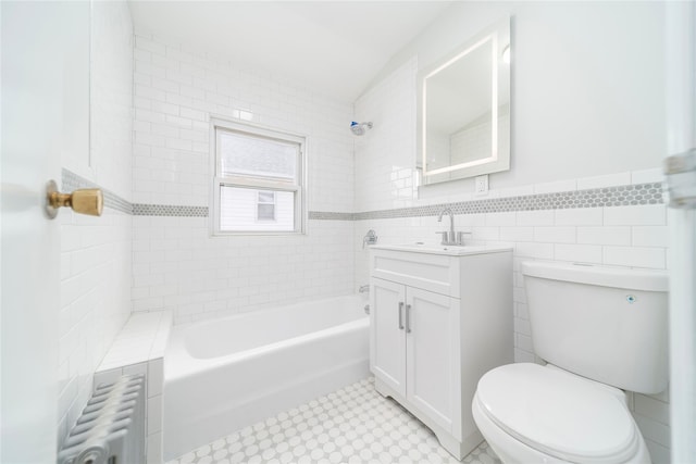 full bathroom featuring toilet, tiled shower / bath, tile walls, radiator heating unit, and vanity