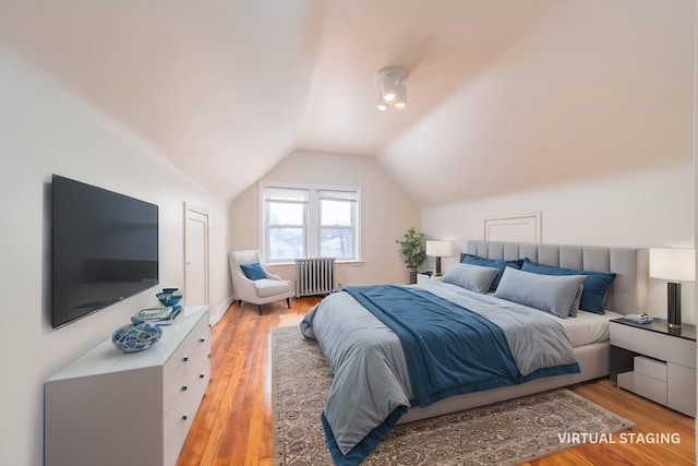 bedroom with vaulted ceiling, radiator, and light hardwood / wood-style floors