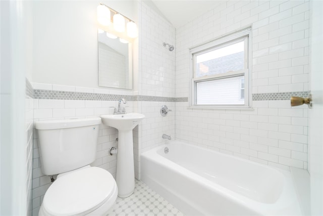 bathroom featuring tile walls, tiled shower / bath, and toilet