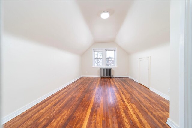 bonus room with radiator, dark wood-type flooring, and vaulted ceiling