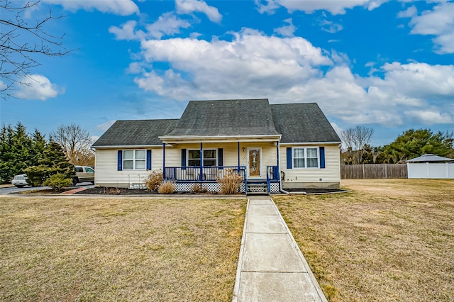 view of front of home featuring covered porch, roof with shingles, fence, and a front yard