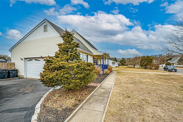 view of side of property featuring driveway, a lawn, and an attached garage