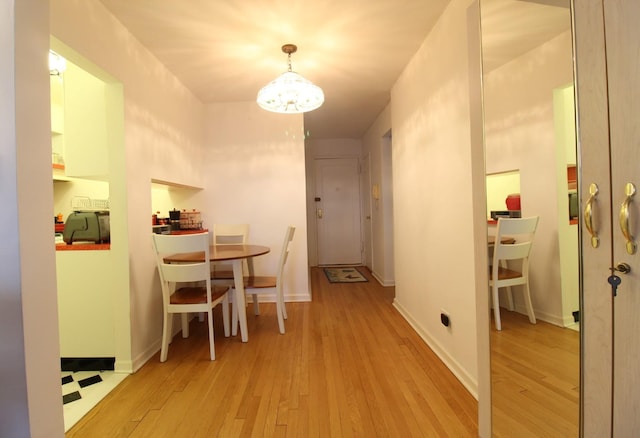 hallway with an inviting chandelier and light hardwood / wood-style flooring