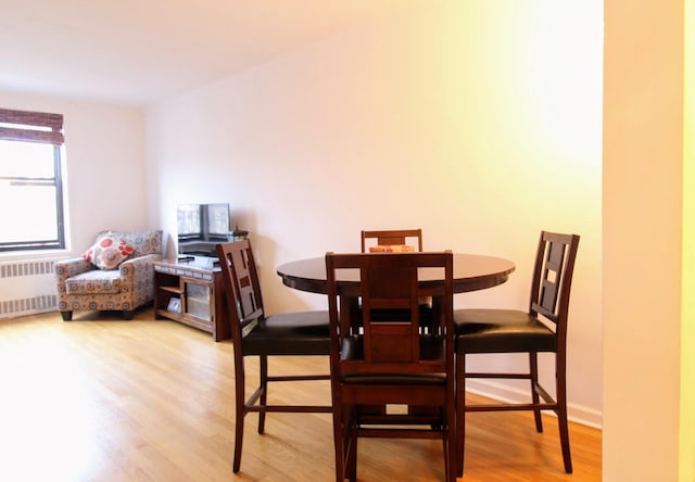 dining area with radiator and light wood-type flooring