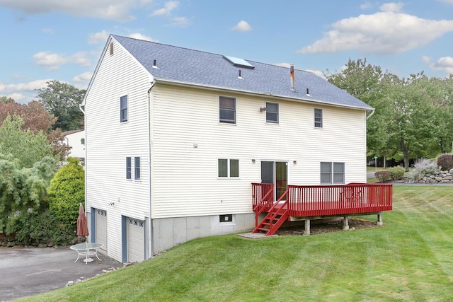 back of property featuring a wooden deck, a garage, and a yard