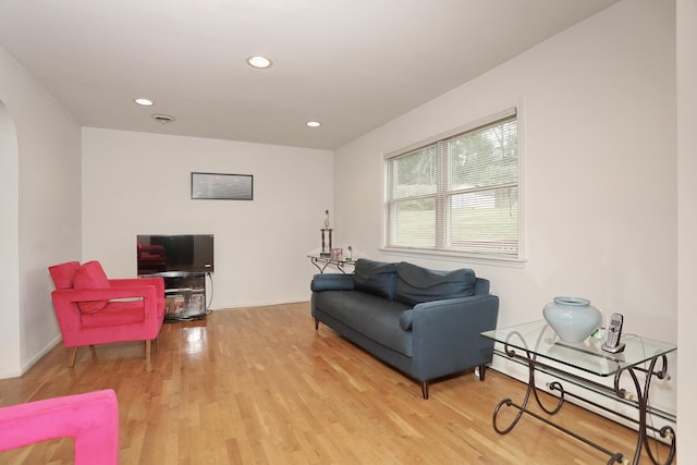 living room with a baseboard heating unit and light hardwood / wood-style floors