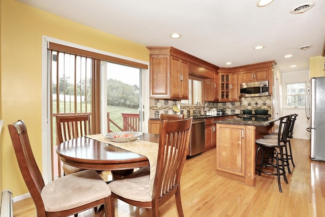 kitchen with a kitchen island, decorative backsplash, light hardwood / wood-style floors, stainless steel appliances, and plenty of natural light