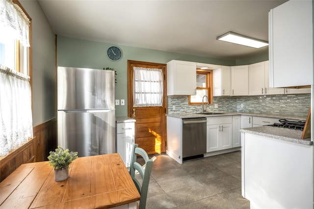 kitchen featuring white cabinetry, sink, decorative backsplash, light tile patterned floors, and stainless steel appliances