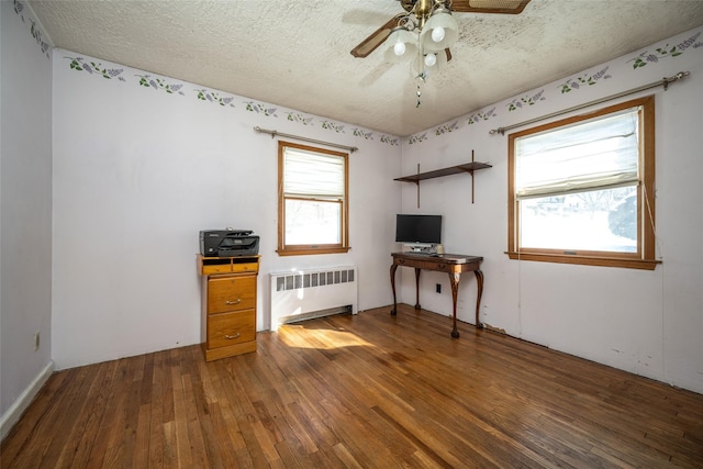 interior space featuring dark wood-type flooring, a healthy amount of sunlight, radiator, and a textured ceiling