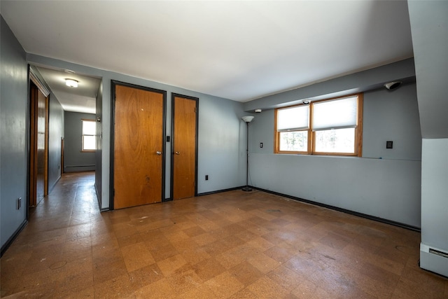 unfurnished bedroom with two closets and baseboard heating