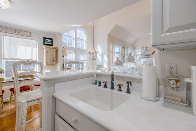 bathroom featuring sink, vaulted ceiling, an inviting chandelier, and plenty of natural light