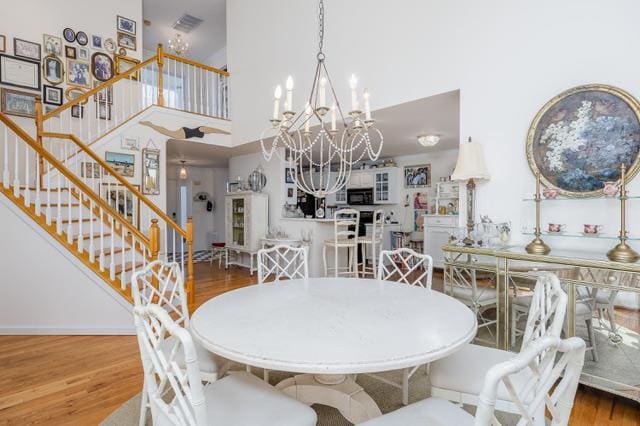 dining space with hardwood / wood-style flooring, a notable chandelier, and a towering ceiling