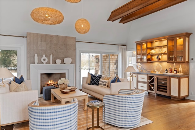 living room with plenty of natural light, bar, beverage cooler, and light wood-type flooring