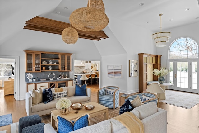 living room with an inviting chandelier, lofted ceiling, and light wood-type flooring