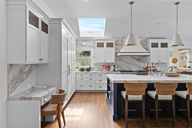 kitchen with premium range hood, a kitchen bar, decorative light fixtures, a kitchen island with sink, and backsplash