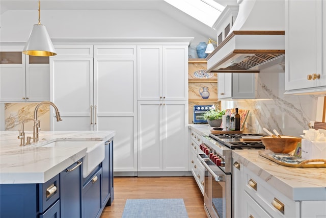 kitchen with premium range hood, blue cabinetry, high end stainless steel range, white cabinetry, and light stone countertops