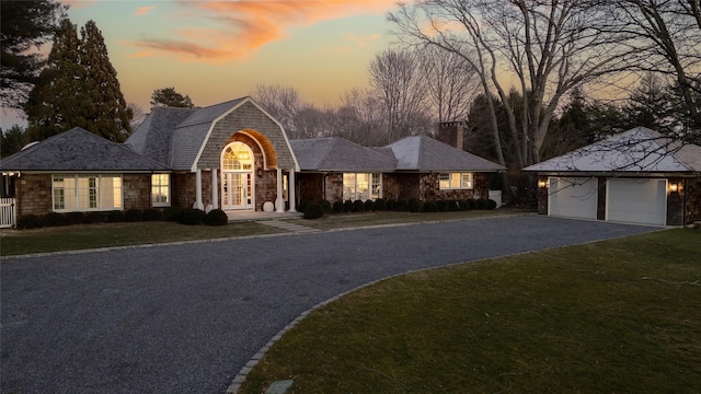 view of front of house with a garage, an outbuilding, and a lawn